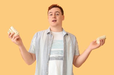 Young man holding doner kebab on beige background