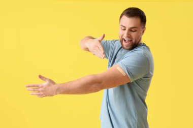 Sarı arka planda uygulamalı tıbbi yaması olan genç bir adam. Aşılama kavramı