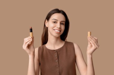 Portrait of beautiful young woman with lipstick on brown background