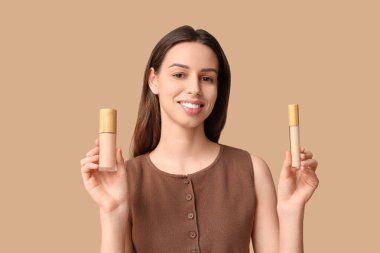 Portrait of beautiful young woman with foundation and concealer on brown background