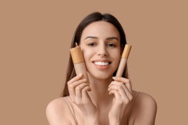 Portrait of beautiful young woman with foundation and concealer on brown background
