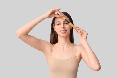 Gri arka planda maskarası olan güzel bir genç kadın.