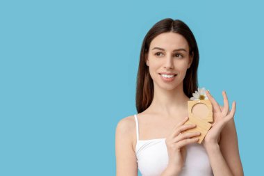 Beautiful young woman with powder and flower on blue background