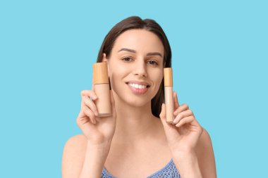 Beautiful young woman with foundation and concealer on blue background