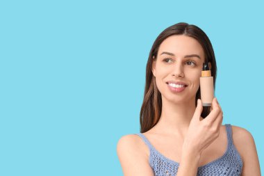 Beautiful young woman with foundation on blue background