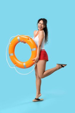 Mavi arka planda halka şamandırası olan güzel, mutlu, Afro-Amerikan kadın cankurtaran.