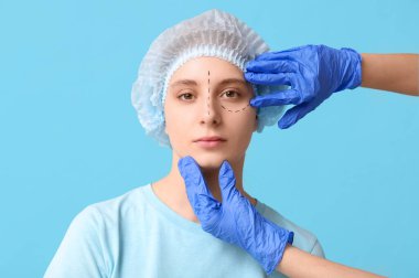 Plastik cerrah mavi arka planda kadının yüzünü inceliyor. Blepharoplasty konsepti