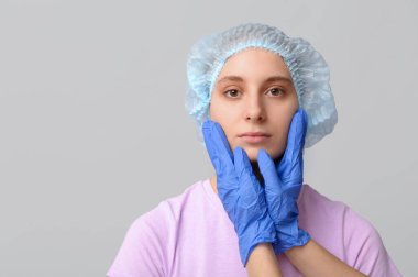 Plastik cerrah gri arka planda kadının yüzünü inceliyor. Blepharoplasty konsepti