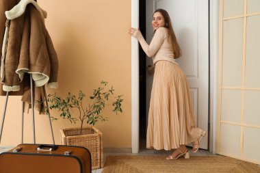 Salonda genç bir kadın kapıyı açıyor.