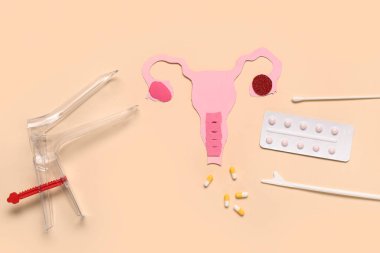 Hap içeren kağıt uterus, pap smear test araçları ve bej arka planda jinekolojik spekulum