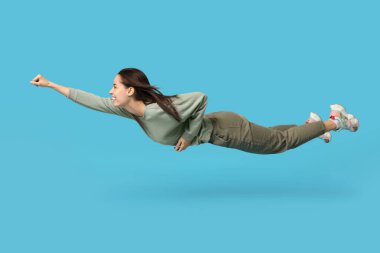 Mavi arka planda uçan neşeli genç kadın