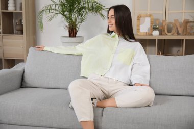 Oturma odasındaki gri kanepede oturan güzel genç bayan.