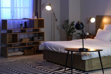 Glowing lamp on table in bedroom at night