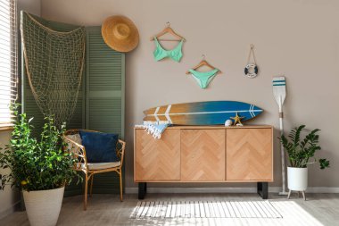 Interior of living room with surfboard and paddle. Summer composition