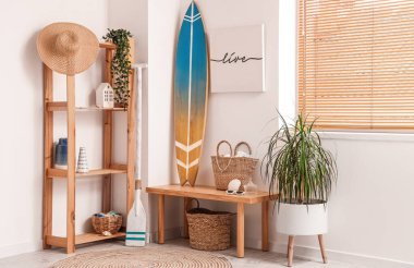 Surfboard, picture, bag and paddle near white wall in room