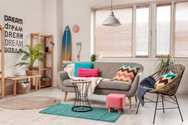 Raflar, sörf tahtası ve gri kanepeli şık bir oturma odası.