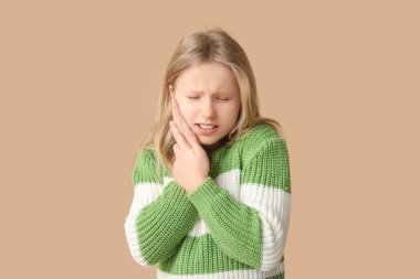 Bej arka planda diş ağrısı çeken genç bir kız.