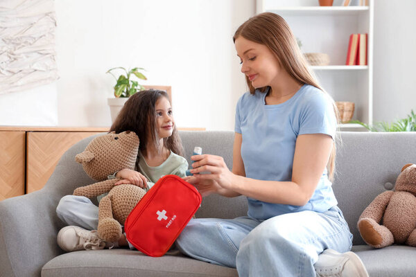 Little girl with toy and her mother taking inhaler from first aid kit at home