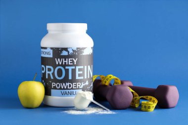 Bottle with protein powder, dumbbells, measuring tape and apple on color background