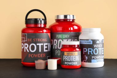 Different bottles with protein powder and scoops on dark table