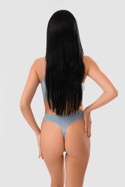 Beautiful young woman in light blue underwear on white background, back view