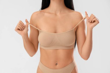 Beyaz arka planda bej rengi iç çamaşırlı güzel bir kadın.