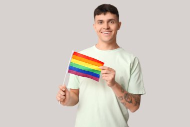 Gri arkaplanda LGBT bayrağı olan yakışıklı genç adam.