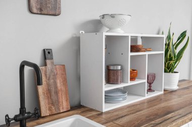 Wooden kitchen counters with shelves and houseplant near white wall