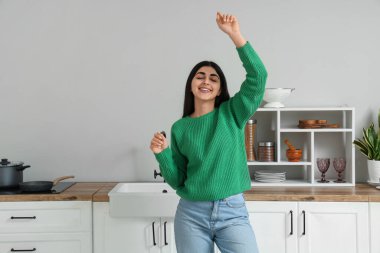 Happy young woman dancing in light kitchen