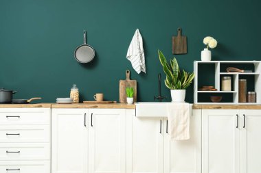 Interior of modern kitchen with white counters, shelves and utensils