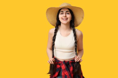 Sarı arka planda Hasır şapkalı güzel, genç ve mutlu bir kadın. Festa Junina (Haziran Festivali) kutlaması