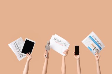 Gazeteli, mikrofonlu ve renkli arka planlı modern aletli kadın eller.