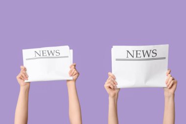 Eflatun arka planda gazeteleri olan kadın eller.