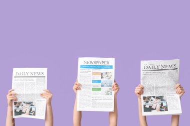 Eflatun arka planda gazeteleri olan kadın eller.