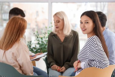 Young Asian woman sitting at group therapy session, closeup