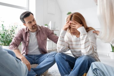 Stressed mature woman sitting at group therapy session