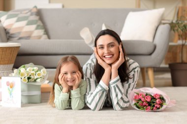 Mutlu bir anne, tatlı küçük kızı ve evde yerde yatan laleleri.