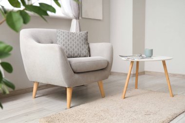Interior of light living room with grey armchair and table
