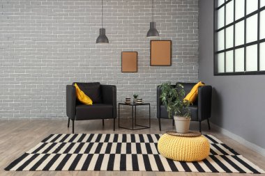 Modern oturma odasının içinde siyah koltuklar, masa ve çerçeveler var.