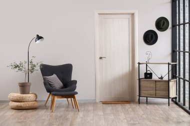 Interior of living room with black armchair, door and shelf unit