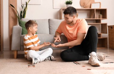 Young man and his little son playing roshambo game at home