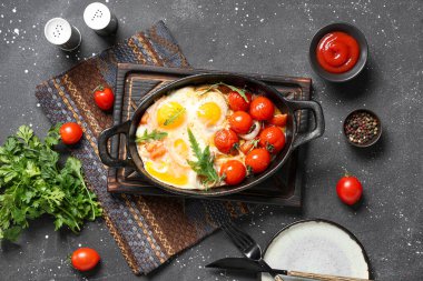 Lezzetli yumurta, domates, baharat ve maydanozlu kompozisyon koyu arkaplanda.