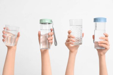 Female hands with bottles and glasses of water on white background, closeup