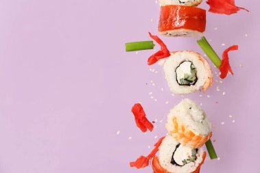 Lezzetli uçan suşi ruloları ve leylak arka planda zencefil.