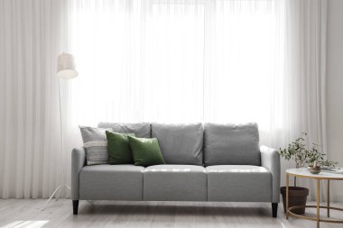 Işıl ışıl oturma odasının içinde rahat gri kanepe ve kahve masasında Tibet şarkı kasesi.