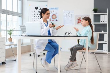 Klinikte küçük bir kızla çalışan kadın göz doktoru.