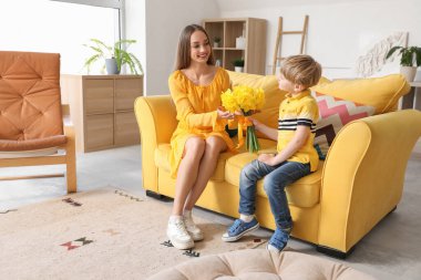 Son greeting his happy mother with bouquet of beautiful narcissus at home