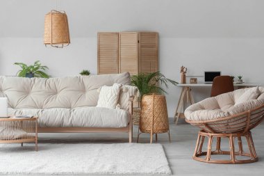 Interior of living room with soft couch, armchair and workplace