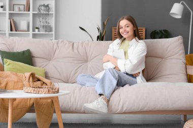 Young woman with tablet computer sitting on sofa at home