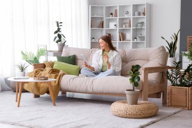 Young woman with tablet computer sitting on sofa at home